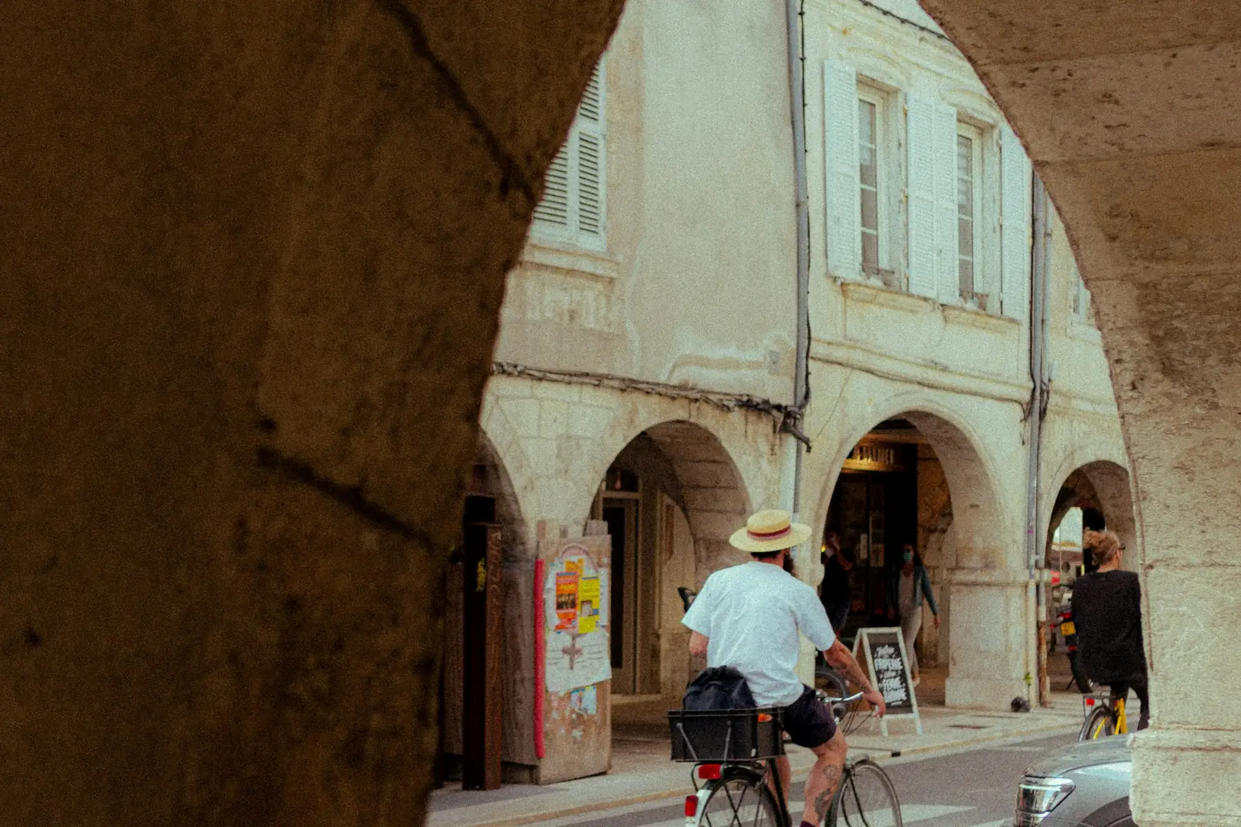 Rue à arcades du centre de La Rochelle vue depuis l’ombre d’une arcade, façades de pierre claire