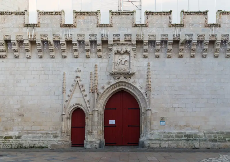 Enceinte gothique de l’hôtel de ville de La Rochelle, mur de calcaire crénelé et portes rouges